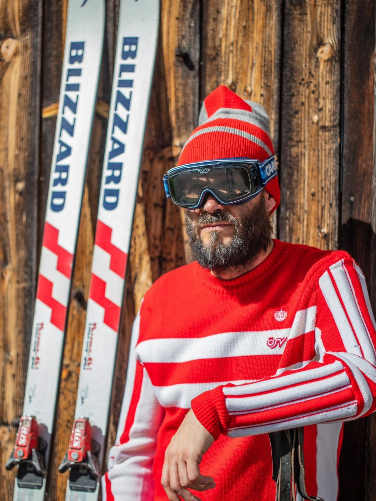 Man in a red and white striped sweater wearing ski goggles and a beanie.