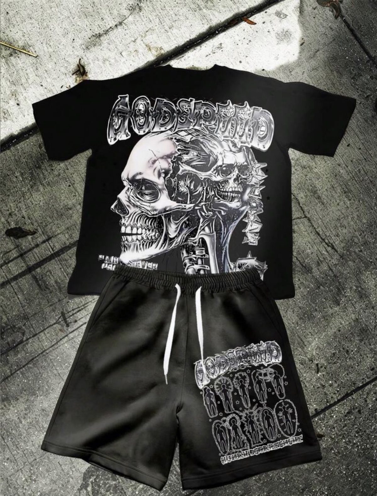 Black graphic t-shirt with skull print and matching black shorts laid on concrete.
