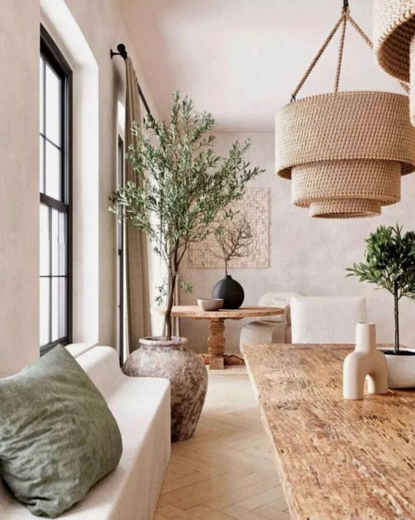 Bohemian living room with rattan lighting, wooden furniture, and a large olive tree in a clay vase.