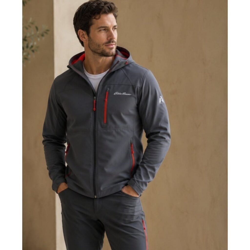 Man wearing a grey Eddie Bauer hooded soft shell jacket with red zipper details.