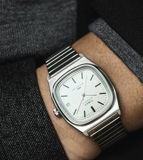 A silver Timex automatic wristwatch with a rectangular face on a man's wrist.