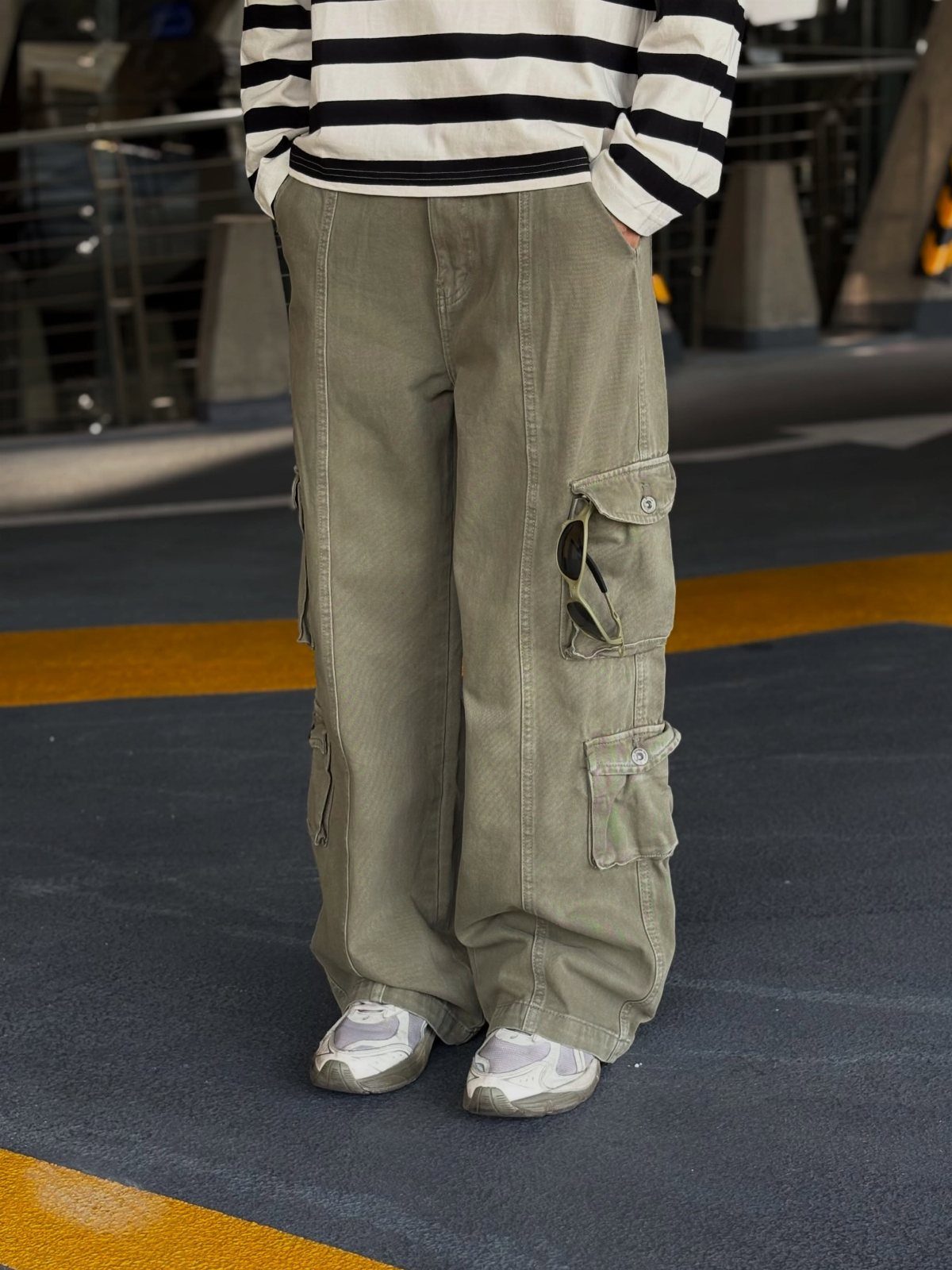 Person wearing a black and white striped top with baggy green cargo pants and white sneakers.