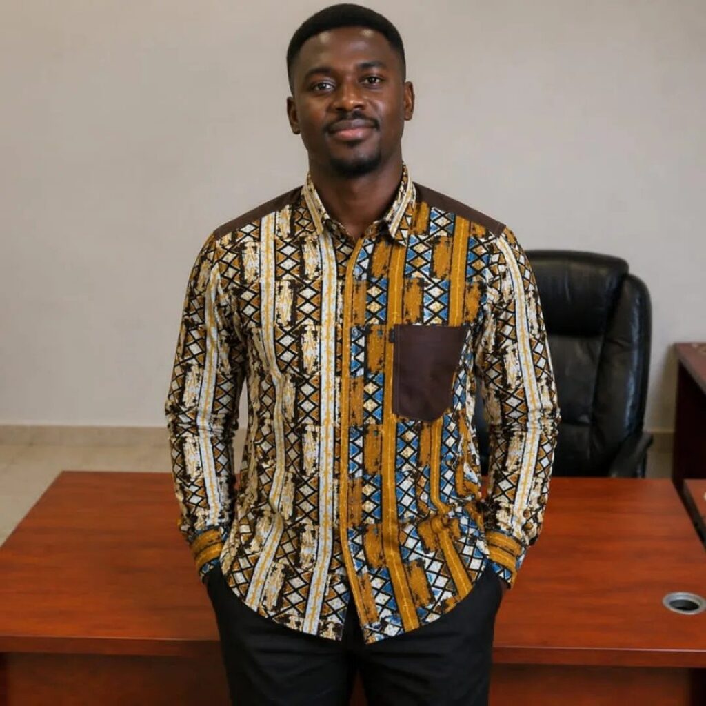 A man wearing a patterned button-down shirt and black pants standing in an office.