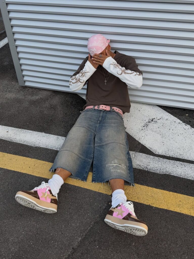 A person sitting on the ground wearing brown and pink statement sneakers with white socks.